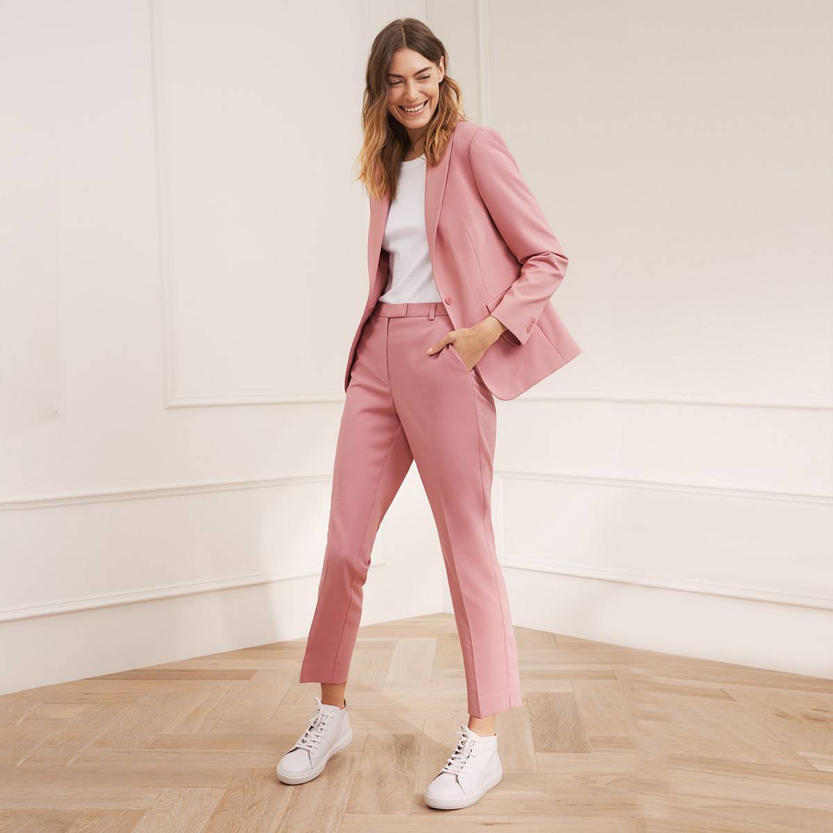 Woman wearing a pale pink two-piece suit. Shop workwear